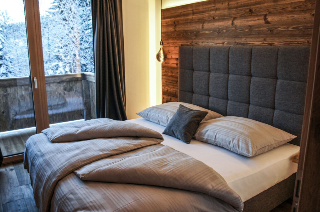Schlafzimmer mit Boxspringbett und winterlichem Bergblick
