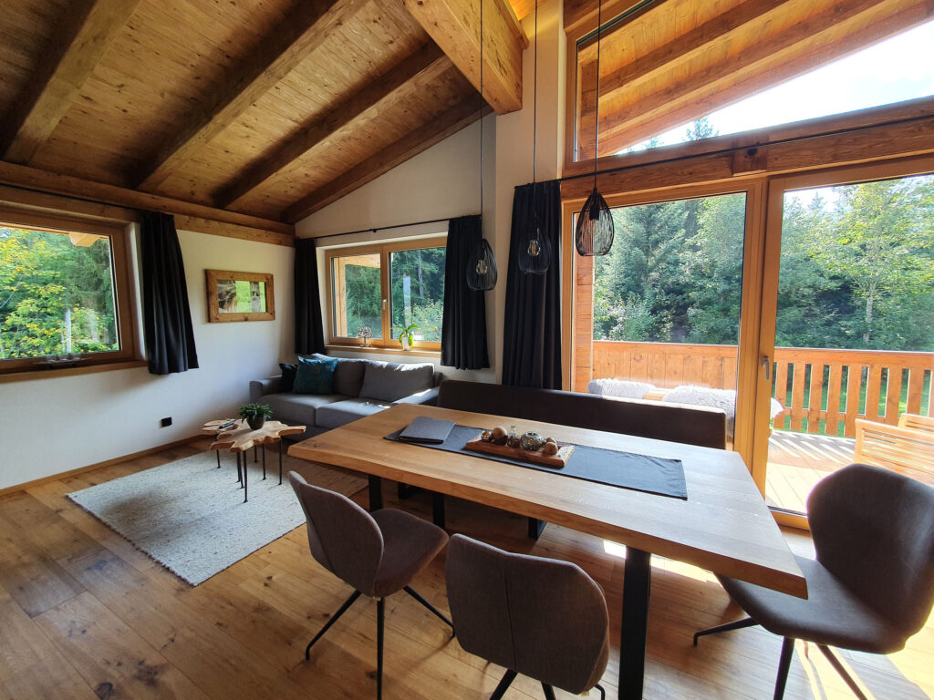 Offener Wohnraum mit Altholztisch, Panoramafenster und Waldsicht