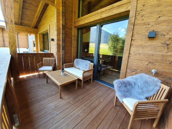 Überdachte Holzterrasse mit Loungemöbeln und ruhigem Waldblick