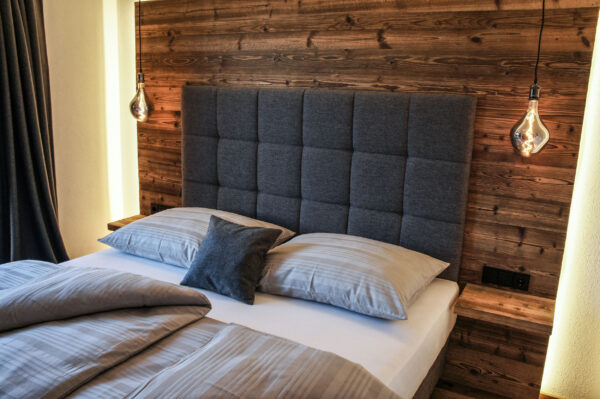 Gemütliches Boxspringbett vor Altholzwand im Schlafzimmer