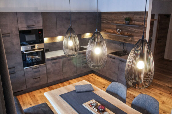 Pendelleuchten über Esstisch in moderner Chalet-Küche