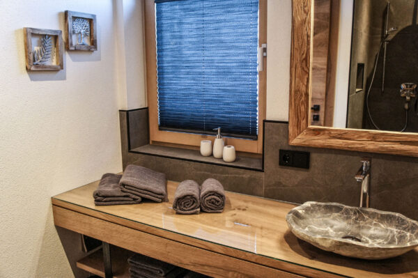 Modernes Chalet-Badezimmer mit Steinwaschbecken, Holzverkleidung und weichen Handtüchern