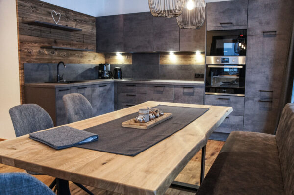 Altholzfronten und großer Esstisch in heller moderner Chaletküche