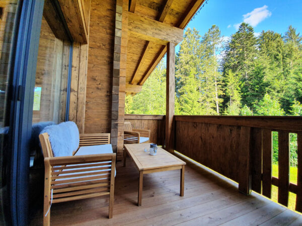Holzbank auf Balkon mit Waldblick und kuscheliger Decke