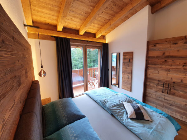 Gemütliches Schlafzimmer mit Blick auf Balkon und Altholzdecke