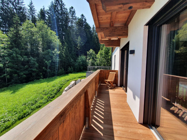 Sonnenbeschienener Holzbalkon entlang der Chaletfassade